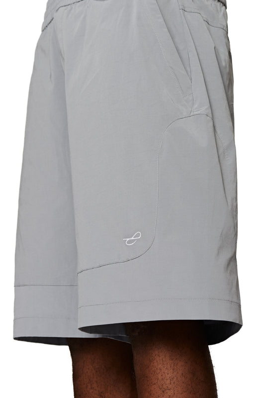 Person wears Terra Track Shorts with wide cut and drawstring, features embroidered E logo and zippered pockets, ideal for unisex styling.