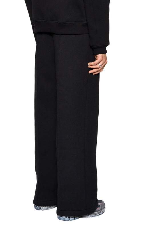 Person trägt Substance Sweatpants Black mit Eingriffstaschen, elastischem Bund und Kordelzug. Lockere Passform, unisex, hergestellt in der EU.