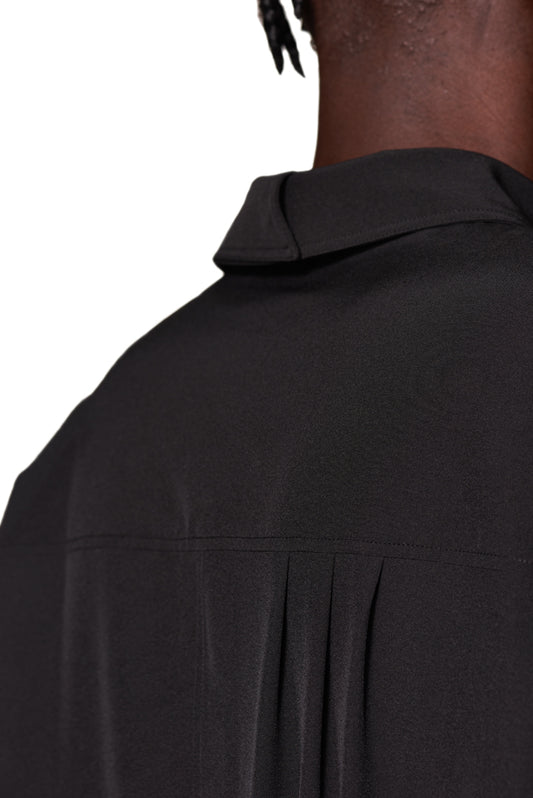 Back view of the CC Button Shirt Black with double collar and breast pocket, oversized fit, unisex. Visible details: dividing seam, yoke with pleats.