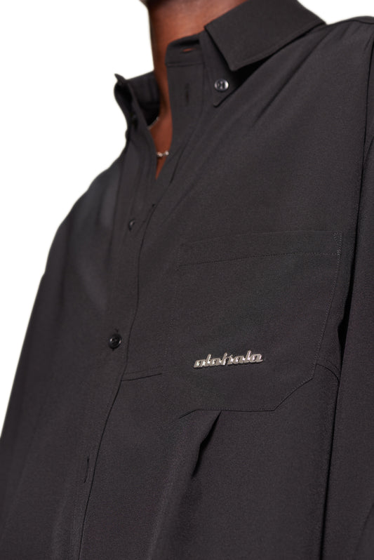 Close-up of the CC Button Shirt Black with double collar, chest pocket with OLAKALA metal logo and dividing seams, in oversized unisex fit.