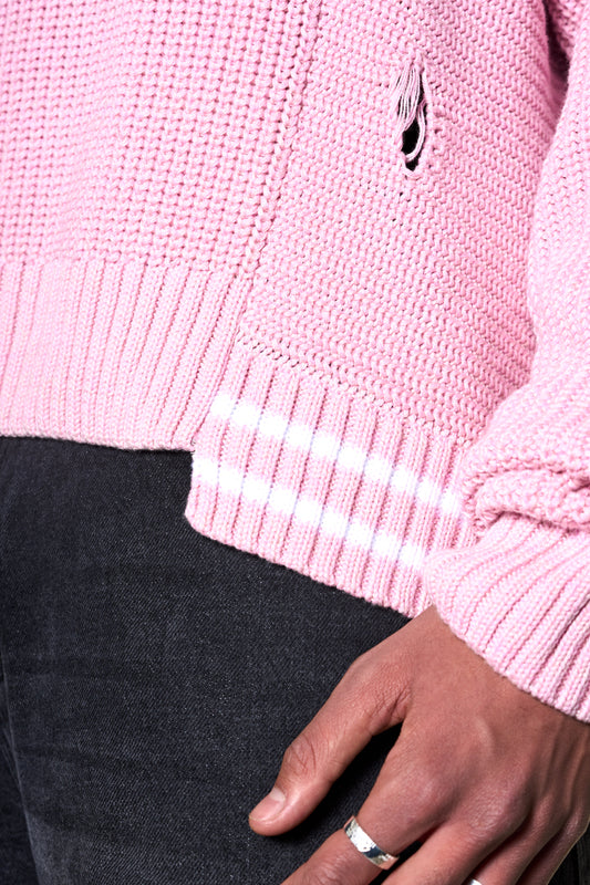 Person wearing Distressed Knit Sweater Pink with detachable OLAKALA pin and offset collar, oversized fit, showing hand with ring.