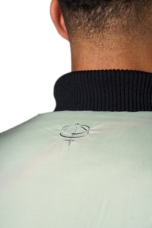 Close-up of a person's neck with the Defect Identity symbol embroidered on the back of the Anatomy Puffer Vest by OLAKALA.