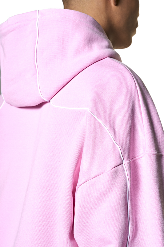 Person trägt Defect ID Hoodie Pink mit feinen Rippbündchen an Ärmeln und Saum, paspelierten Nähten und grafischem Siebdruck auf der Brust. Oversized, cropped Fit.