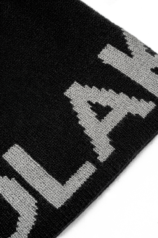 Nahaufnahme der Light Logo Beanie Black, zeigt gestrickte, pixelartige graue Buchstaben auf schwarzem Hintergrund, passend zum stilvollen Angebot des offiziellen OLAKALA® Onlineshops.