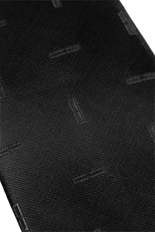 Close-up of the Monogram Tie Black with a subtle, tone-on-tone woven pattern of small rectangular stitch motifs. Unisex design, ideal for elegant occasions.