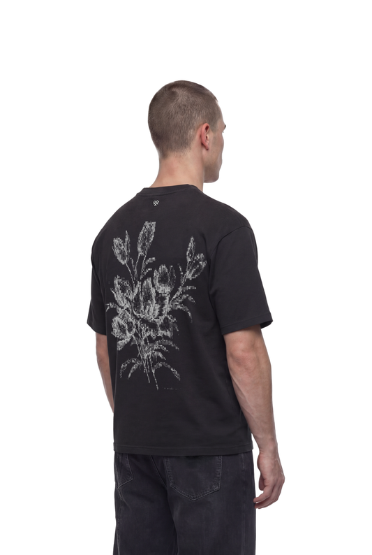 Mann von hinten mit Heart T-Shirt Black, großer Blumenstrauß-Print auf Rücken, getragen mit dunklen Jeans.