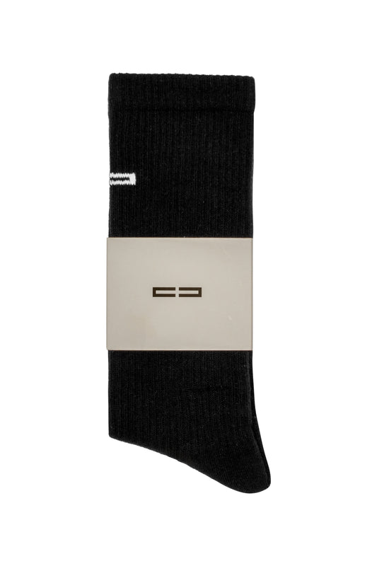 Linen Socks Black aus Rippstrick mit weißem Streifen und gesticktem OLAKALA Logo, präsentiert mit einem minimalistischen Papierband.