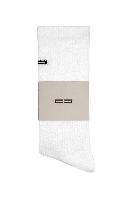 Single white, ribbed crew sock Linen Socks White with embroidered OLAKALA logo near the cuff, held in place by a light brown paper band.