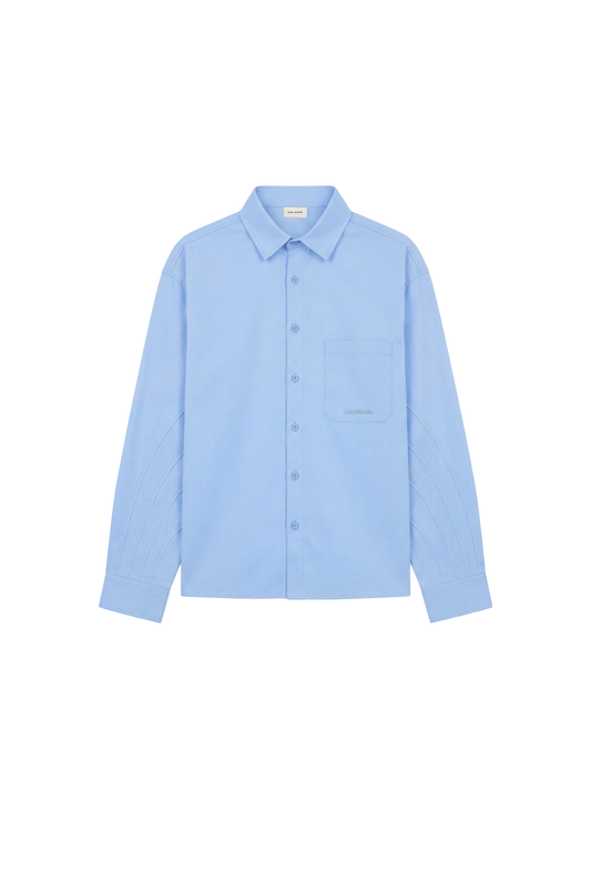 CC Anatomy Shirt Blue mit klassischem Kragen, Knopfleiste, Brusttasche mit OLAKALA-Logo, subtilen Nähten und lockerer, unisex Passform, flach präsentiert.