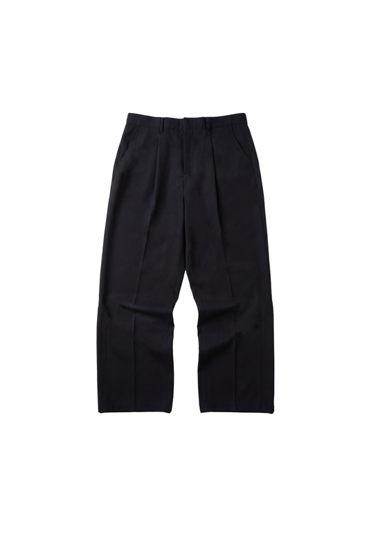 CC Dress Pants Regular Black: Schwarze, gerade geschnittene Hose mit französischen Taschen, asymmetrischem Eingriff, Bundfalten und gesticktem OLAKALA-Logo über der rechten Gesäßtasche.