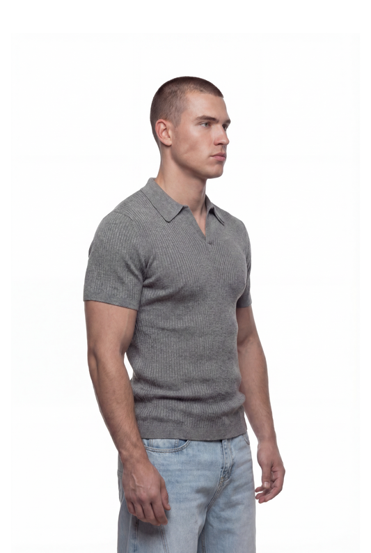 Junger Mann trägt das CC Core Rib Knit Polo Gray mit moderner, kastiger Silhouette und knopflosem Kragen, kombiniert mit hellen Jeans.