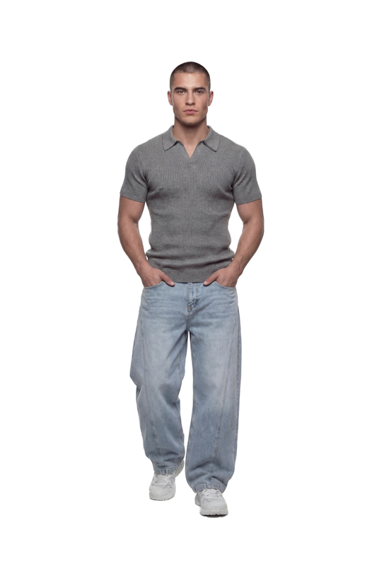 Junger Mann im CC Core Rib Knit Polo Gray, modern und boxy, ohne Knöpfe, kombiniert mit hellen Jeans und weißen Sneakers.
