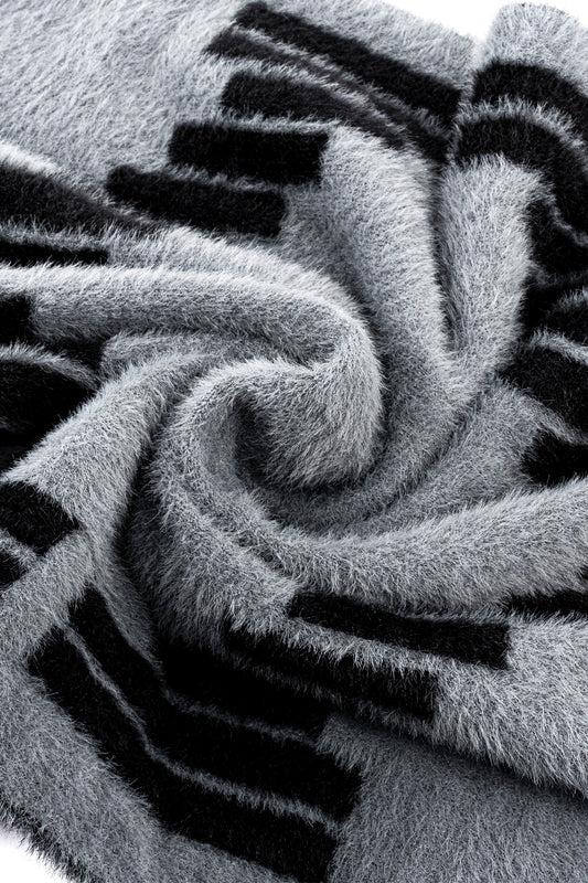 Nahaufnahme des Fuzzy Logo Schals mit OK-Logomuster, aus flauschigem Material, unisex, Länge 175 cm, Breite 40 cm.