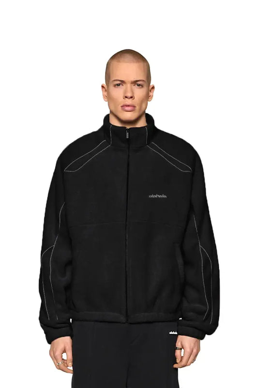 Mann trägt Reflective Fleece Jacket Black mit reflektierenden Nähten und OLA KALA Stickerei auf der Brust, oversized Fit, Gummizug an Ärmeln und Bund.