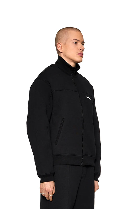 Substance Sweatjacket Black: Man wears black jacket with ribbed collar, zippered pockets and OLAKALA silicone patch on the chest. Unisex, made in the EU.