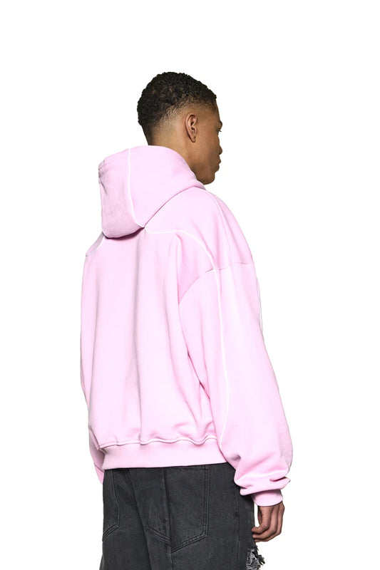 Mann trägt Defect ID Hoodie Pink mit Siebdruck-Grafik auf der Brust, Rippbündchen und paspelierten Nähten, oversized und cropped Fit.