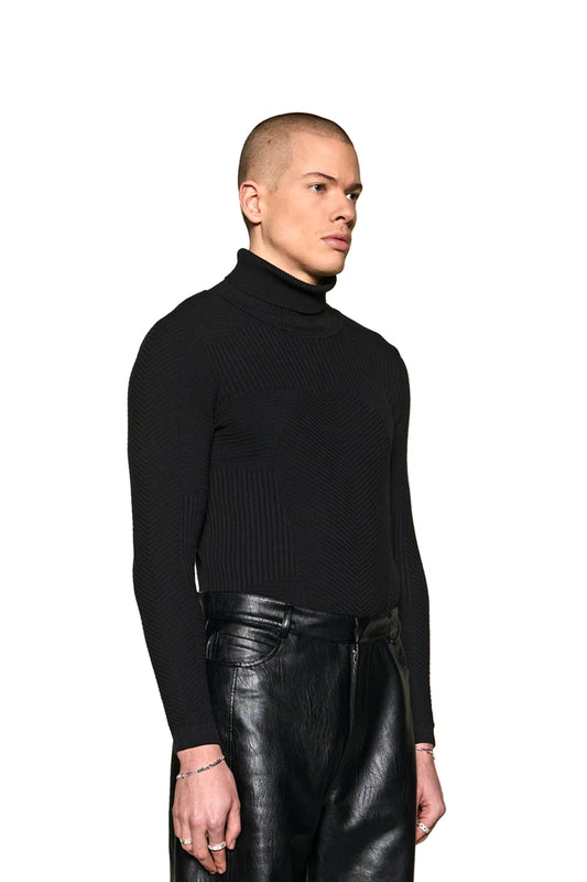 Mann trägt Anatomy Turtleneck mit eng anliegendem Schnitt und OLA KALA Tag, kombiniert mit schwarzen Lederhosen.