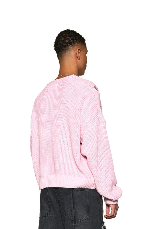 Man wears Distressed Knit Sweater Pink with detachable pin, offset collar and knitted-in details. Oversized fit, unisex, features a pocket and hand.