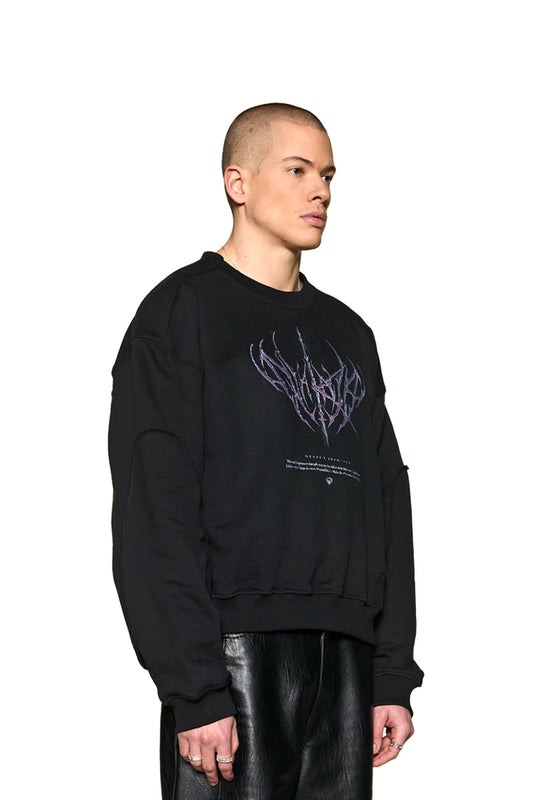Man wears Defect ID Sweater Black with Defect Identity graphic on the chest, oversized fit and ribbed cuffs and hem.