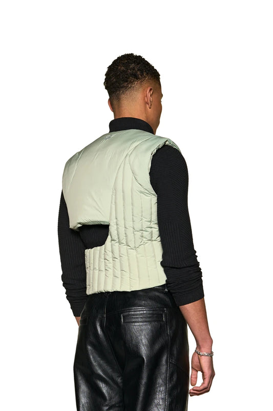 Man wears Anatomy Puffer Vest with asymmetric cut, 3M filling material, adjustable width, zipper and flap pockets, embroidered OLAKALA logo and Defect Identity icon.
