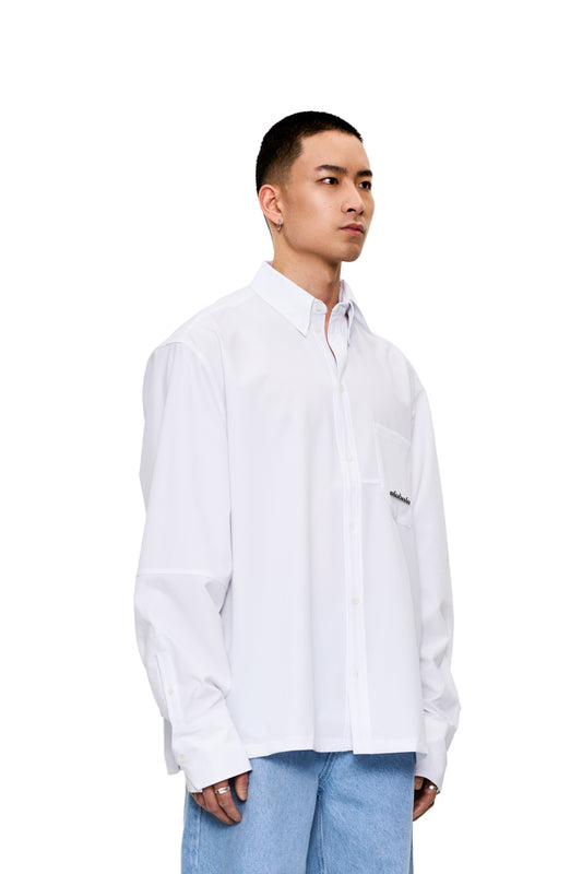 Mann trägt das CC Button Shirt White mit doppeltem Kragen, Brusttasche mit Metall-Logo und Teilungsnähten, oversized Unisex-Design von OLAKALA.