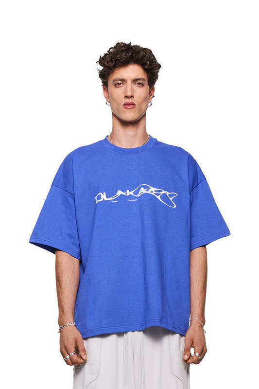 Mann trägt Synergy T-Shirt Blue mit großem weißen Synergy-Logo auf der Brust, oversized Fit, unisex, präsentiert von OLAKALA.