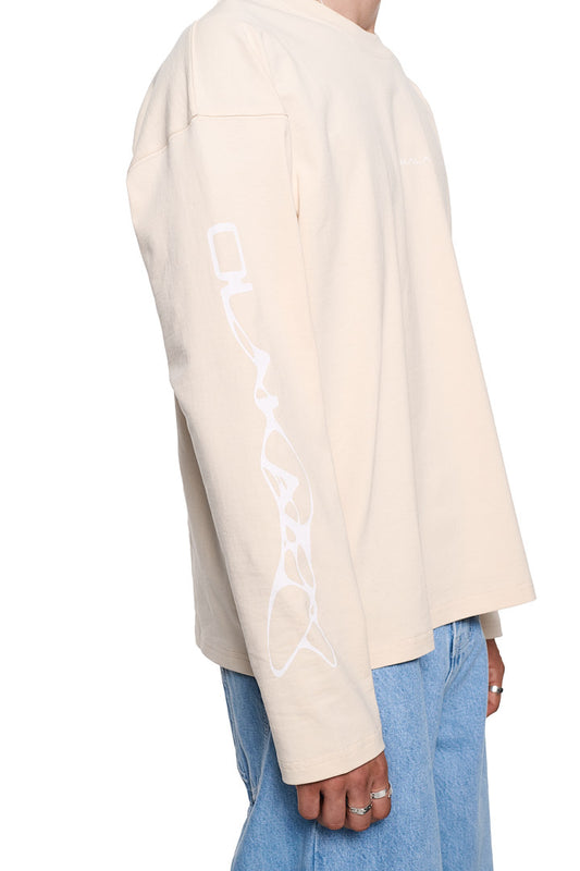 Person trägt das Synergy Longsleeve Shirt Beige von OLAKALA mit Siebdruck-Logos auf Brust und Ärmeln, zeigt Ripp-Kragen und oversized Unisex-Passform.