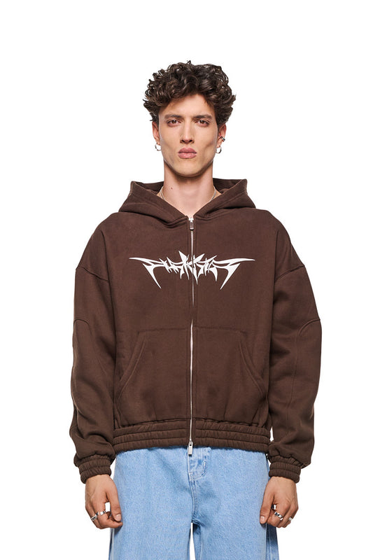 Isolation Zip Hoodie Brown mit 2-Wege-Reißverschluss, Eingriffstaschen, elastischen Bündchen und Isolation-Grafik, getragen von einem Mann mit lockigem Haar. Unisex, Oversized-Passform.