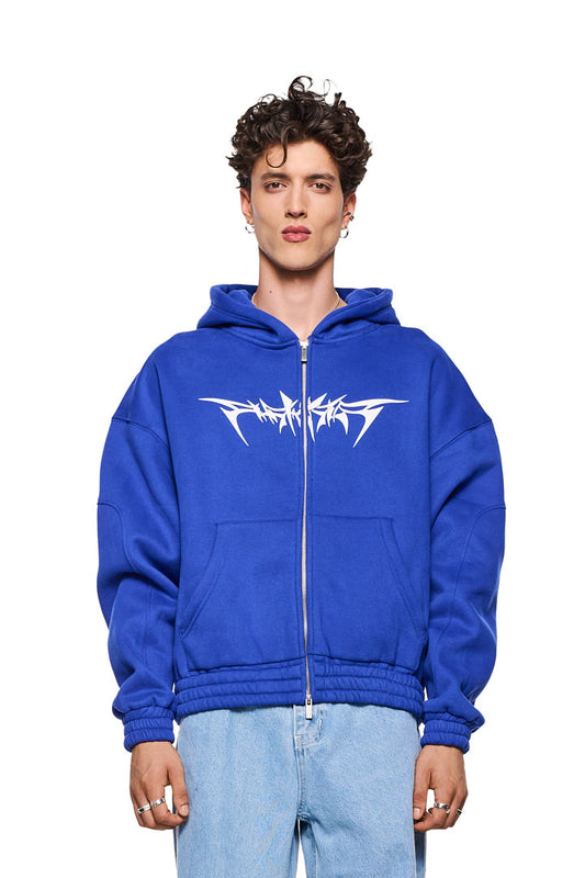 Mann trägt Archive Isolation Zip-Hoodie Blau mit 2-Wege-Reißverschluss, Teilungsnähten und elastischen Bündchen. Oversized Passform, unisex Design.