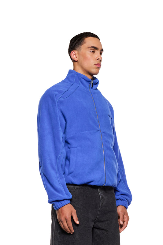 Mann trägt Fleece Jacket Dazzling Blue mit Paspelierung, elastischen Bündchen und eingesticktem OLAKALA-Logo auf der Brust.