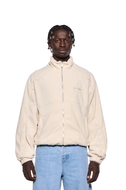 Mann trägt Fleece Jacket Almond Milk mit gesticktem OLAKALA-Logo, Paspelierung, Eingriffstaschen, elastischen Bündchen und oversized Passform.