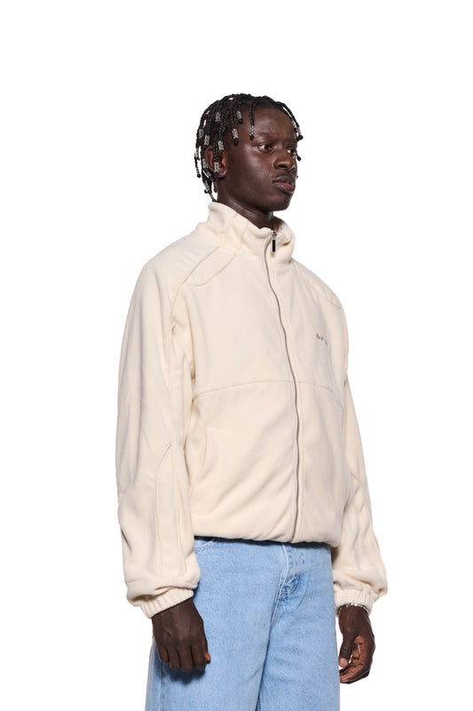 Ein Mann trägt die Fleece Jacket Almond Milk von OLAKALA mit gesticktem Logo, elastischen Bündchen und Paspelierung, zeigt die Oversized Unisex-Passform.