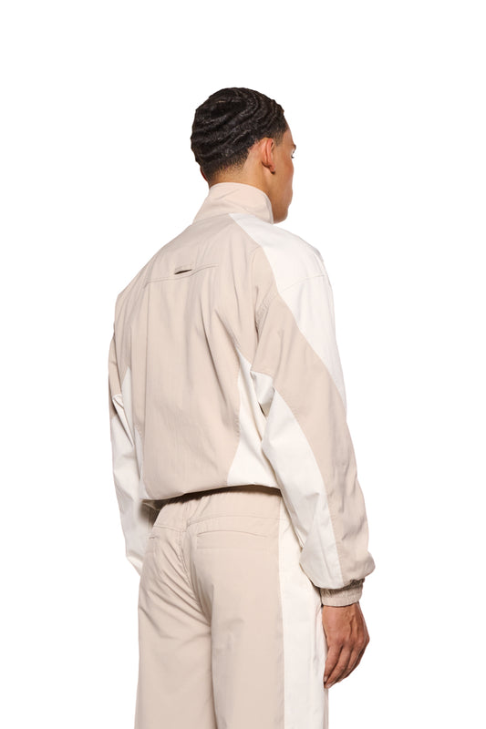 Mann in weiß-beiger Sports Tracksuit Jacke Sand mit elastischem Bund, Kordelzug, gesticktem OLAKALA Sports Logo und Reißverschlusstaschen, lockere Passform.