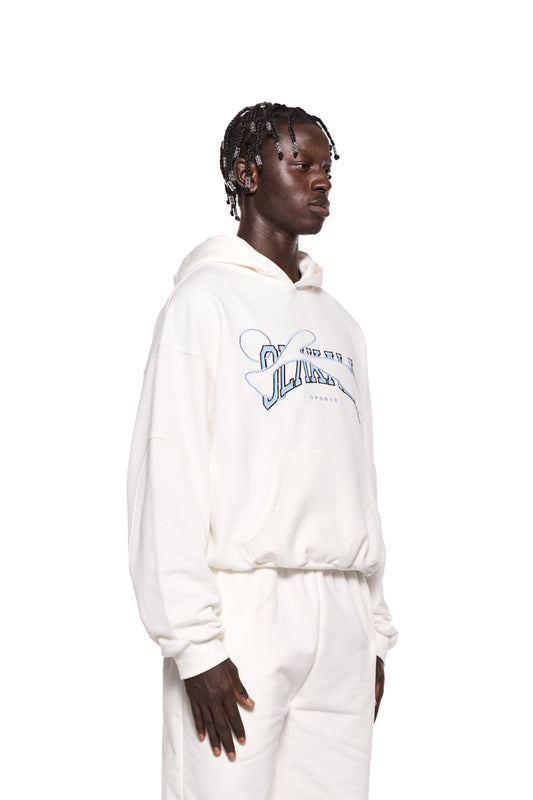 Ein Mann trägt das Sports Hoodie White mit gestickter OLAKALA Sports Grafik, Teilungsnähten und Ripp-Bündchen, präsentiert in einer oversized Unisex-Passform.