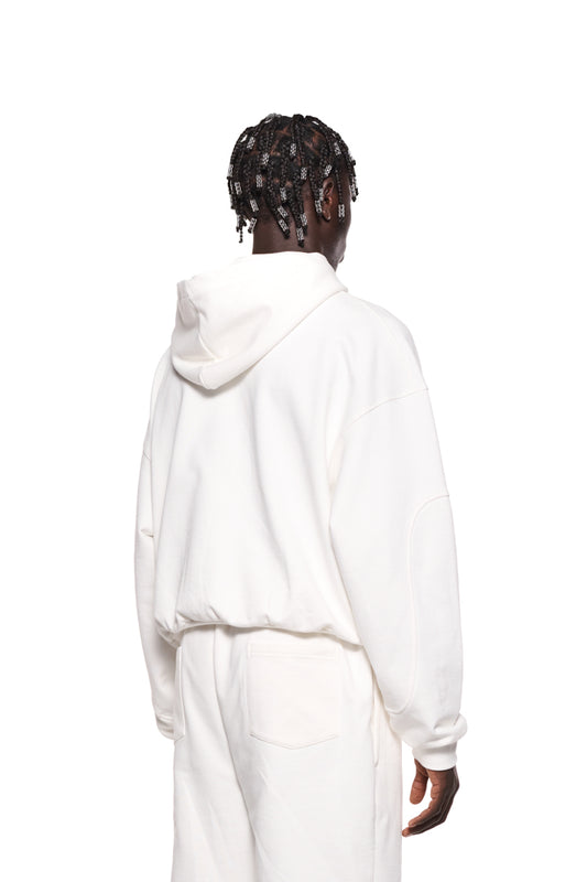 Person trägt einen weißen Sports Hoodie mit gestickter OLAKALA Sports Grafik auf der Brust, Ripp-Bündchen und Teilungsnähten an den Ärmeln, oversized Passform, unisex.
