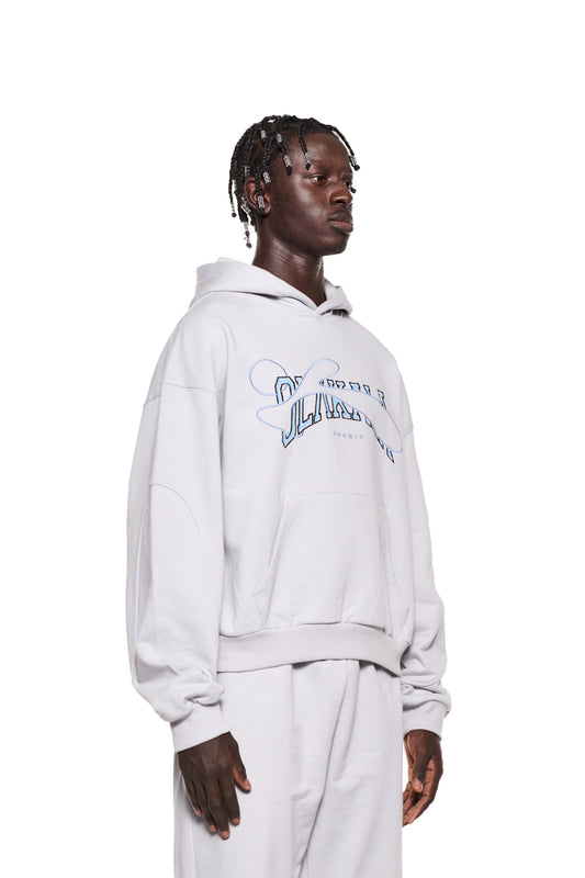 Ein Mann trägt ein Sports Hoodie Gray mit gestickter OLAKALA Sports Grafik, Teilungsnähten an den Ärmeln und Ripp-Bündchen, oversized und unisex.