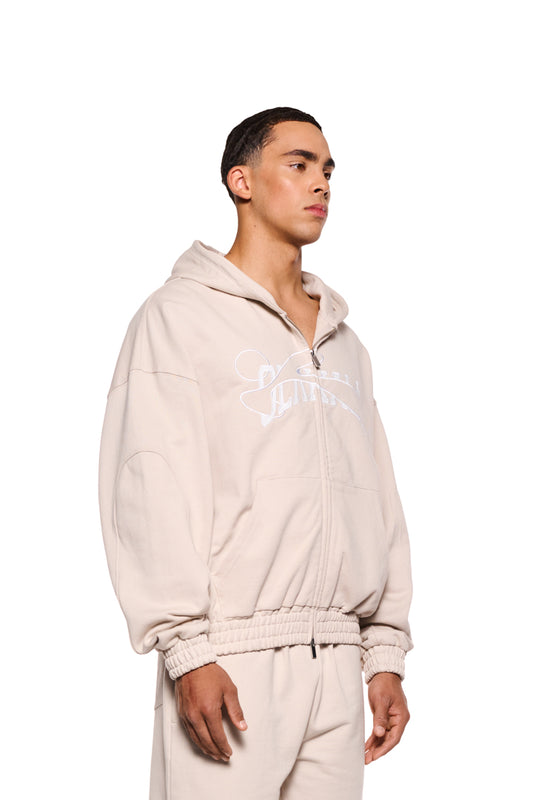 Mann trägt Sports Zip Hoodie Beige mit gestickter OLAKALA Sports Grafik, 2-Wege-Reißverschluss, elastischen Bündchen und Oversized-Passform.