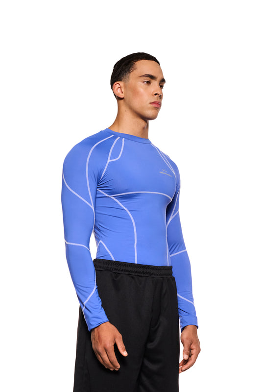 Mann im eng anliegenden Sports Anatomy Tech Top Blue mit OLAKALA Sports Logo auf der Brust und Ziernähten, aufgenommen im offiziellen OLAKALA® Onlineshop.