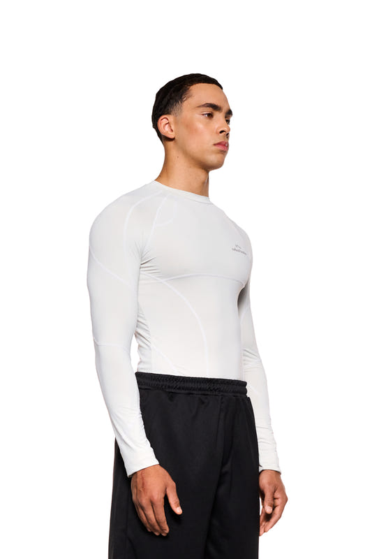 Man in white longsleeve with decorative stitching and OLAKALA Sports logo on the chest, close fit. Product: Sports Anatomy Tech Top Gray.
