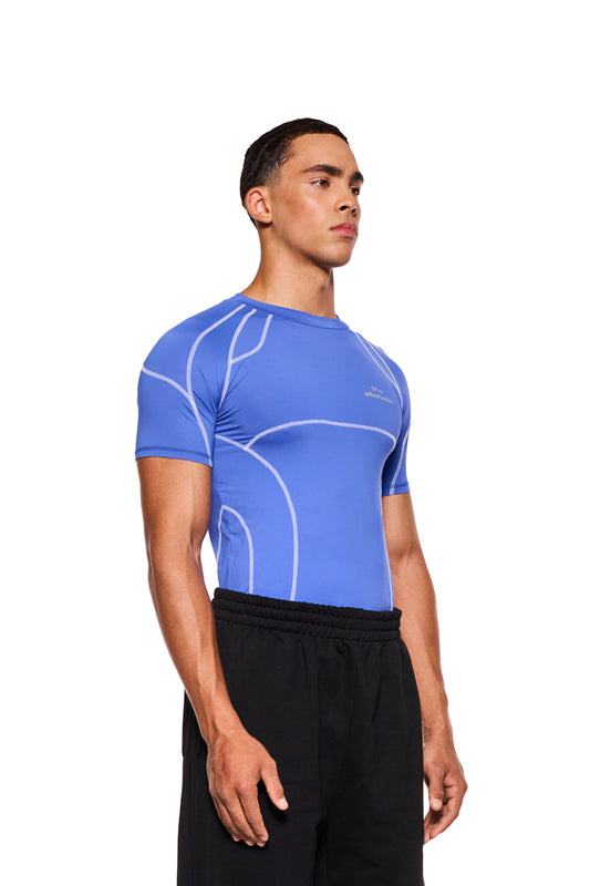 Mann trägt eng anliegendes Sports Anatomy T-Shirt Blau mit Ziernähten und OLAKALA Sports Logo auf der Brust, unisex Design.