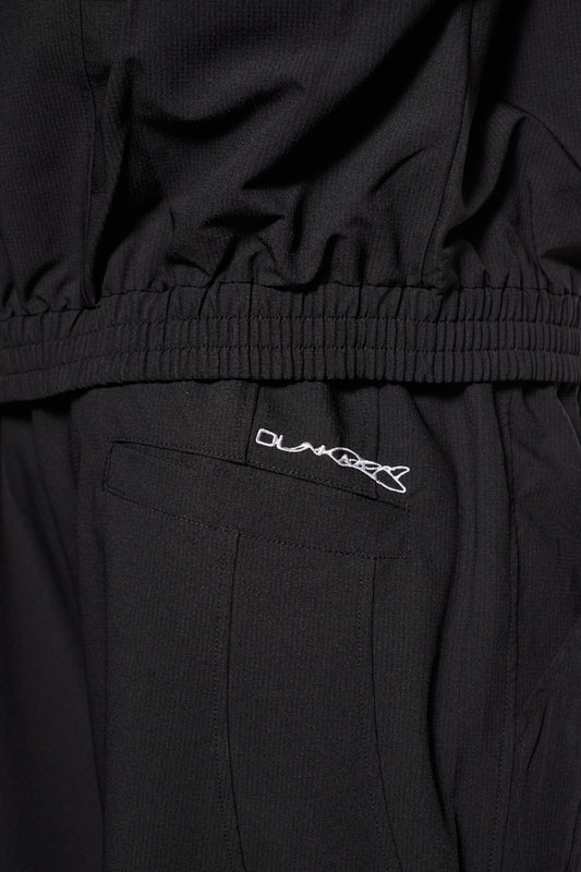 Synergy Cargo Pants Black mit Teilungsnähten, elastischem Kordelzug, Cargo-Taschen und gesticktem Synergy-Logo, Fokus auf Stoff und Taschen-Details.