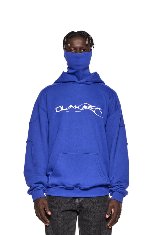 Mann trägt Synergy Mask Hoodie Blue mit Synergy-Grafik, Rippbündchen und Kapuze. Gesicht teils verdeckt durch integrierte Maske. Oversized, unisex Design.