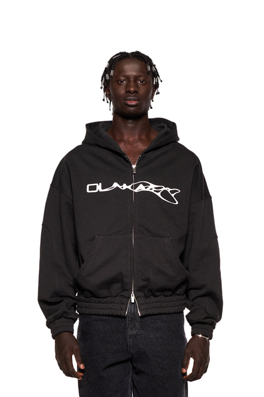 Mann trägt Synergy Zip Hoodie Black mit 2-Wege-Reißverschluss und Synergy-Logo auf der Brust, oversized Unisex-Design.