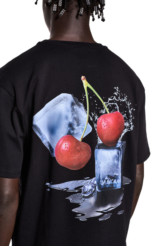 Person trägt NC T-Shirt Black Regular mit Grafik Neighbor's Cherries auf dem Rücken und gesticktem OLA KALA Logo auf der Brust.
