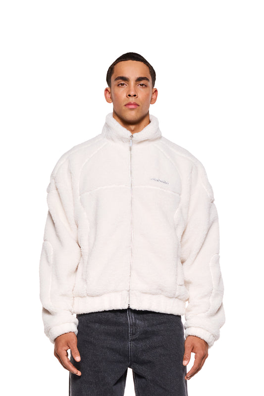 Mann trägt Teddyjacke Off White mit hohem Kragen, Teilungsnähten, Sticklogo und Eingriffstasche. Oversized, cropped Unisex-Design von OLAKALA.