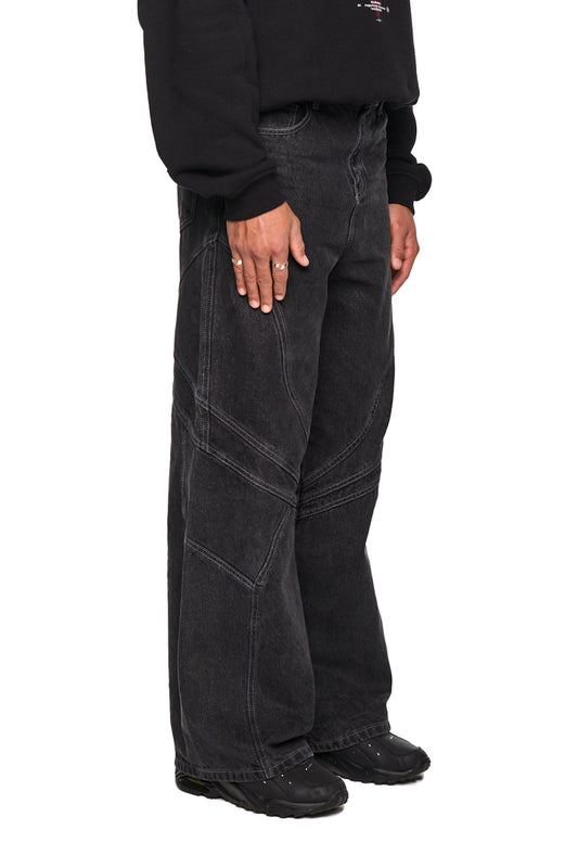 Person trägt Alien Intel Black Denim Pants mit geradem Bein und lockerer Passform. Detailreiche Teilungsnähte und 5-Pocket-Style betonen die robuste Denim-Qualität.