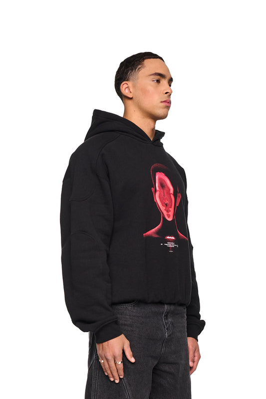 Mann trägt Alien Intel Mask Hoodie Red, oversized mit Siebdruck-Grafik und Teilungsnähten, sichtbare Ripp-Bündchen und elastischer Saum, präsentiert von OLAKALA.