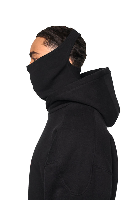 Mann trägt Alien Intel Mask Hoodie mit Siebdruck, Oversized-Cropped-Fit und Ripp-Details an Ärmeln und Saum. Unisex-Design.
