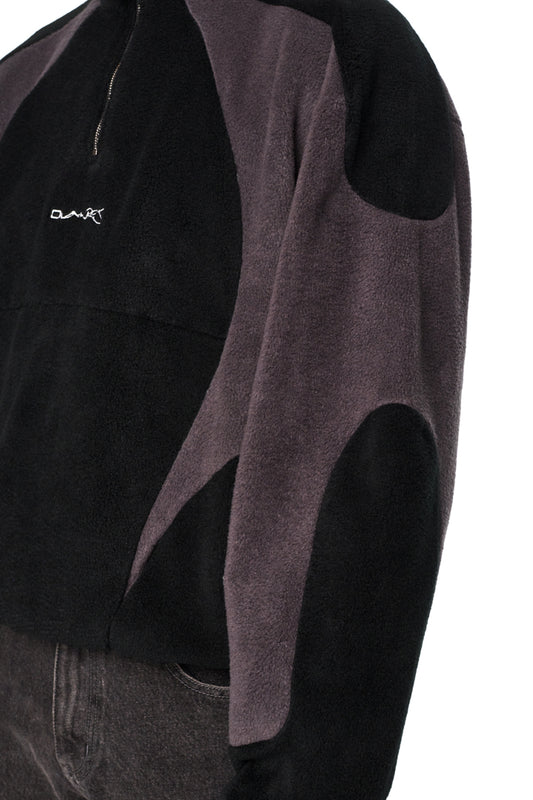 Nahaufnahme der Alien Intel Fleece Halfzip Black Jacke mit hohem Kragen, Reißverschluss auf der Brust und gesticktem „Synergy“-Logo auf weichem Fleece-Stoff.