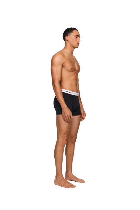 Mann in schwarzen CC Boxershorts Black 3er Pack von OLAKALA, zeigt muskulösen Oberkörper. Elastischer Bund mit Logo, Rückgabe ausgeschlossen.